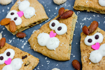 Easter bunny cookies scones decorated with cream and almonds like a funny bunnies face , Easter treats for kids