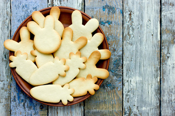 Easter treats for kids - shortbread bunnies and carrots on wooden background with copyspace