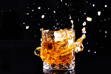 Isolated shot of whiskey with splash on black background, brandy in a glass