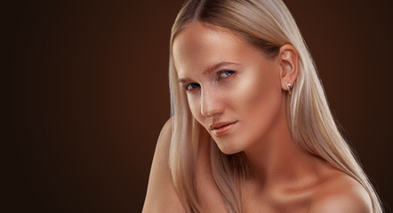Beautiful girl with bronze skin. Golden shining makeup on the dark background