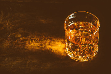 whiskey with ice cubes on wooden background