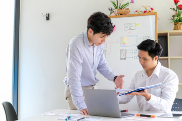 Obraz premium Two young asian man designer website applications consulting and planning work together. Job training to colleagues.