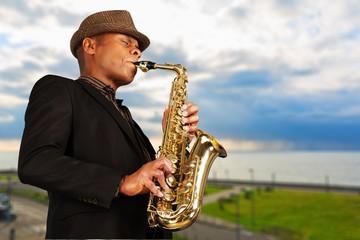 Close-up man playing on saxophone on blurred