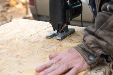 cutting an osb panel with a jigsaw, hand on the panel