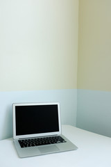 Laptop on white table top modern home office desk workspace on pale blue and yellow pastel color background with empty copy space. Creative, freelance and minimal office. Retro interior design.