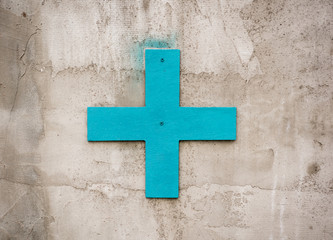 Blue plus sign for decoration on the concrete wall outdoors
