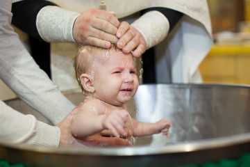 Priest pours water on the infant at baptism. Orthodox rite of baptism. Acceptance of faith. Child in the font