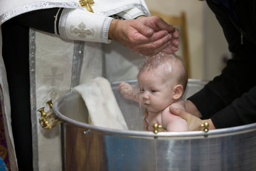 Priest pours water on the infant at baptism. Orthodox rite of baptism. Acceptance of faith. Child...