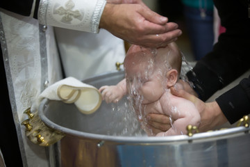Priest pours water on the infant at baptism. Orthodox rite of baptism. Acceptance of faith. Child in the font