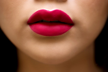 Fototapeta premium Cosmetics, makeup and trends. Bright lip gloss and lipstick on lips. Closeup of beautiful female mouth with red lip makeup. Beautiful part of female face. Perfect clean skin, white teeth.