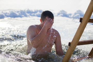 Belarus, the city of Gomel. Icy lake. January 19, 2019. The Feast of the Baptism of Jesus.A man is plunged into an ice-hole.Bathing in ice water. The Baptism of Jesus. Religious holiday