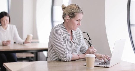 Businesswoman in a café using a laptop - Powered by Adobe