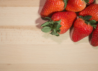Strawberries on natural wooden table, top down with space to left