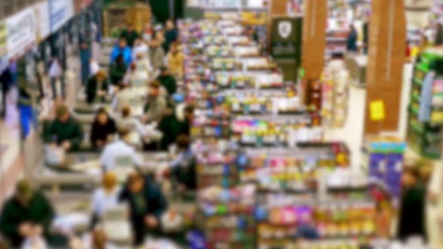Cashier at supermarket / Retail checkout / Paying groceries. Unrecognizable buyers with carts move in queues to pay for purchases at the supermarket cashier. Slow motion.