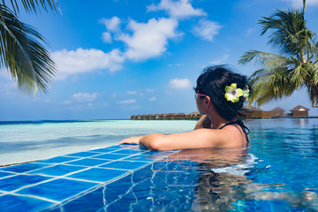 Girl looking at the ocean while sitting by the pool