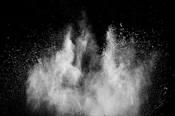 White powder explosion isolated on black background. White dust particles splash.Color Holi...