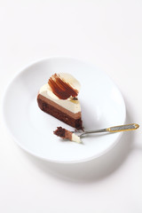 Slice of Three Chocolate Mousse Cake decorated with chocolate petal, on white plate, on white background.