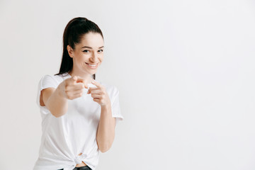 Fototapeta premium Happy woman standing and presenting something isolated on gray studio background. Beautiful female half-length portrait. Young emotional woman. The human emotions, facial expression concept.