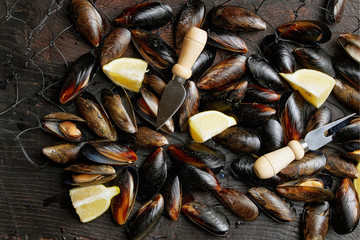 Many mussels with lemon slices in the net, water spray