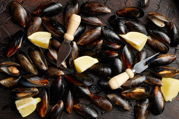 Many mussels with lemon slices in the net, water spray