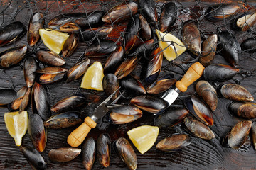 Many mussels with lemon slices in the net, water spray