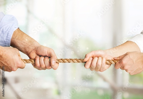 Business people pulling rope in opposite directions at office