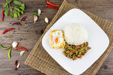 Spicy Thai basil with Crispy Chicken and Egg (Pad Krapow Gai) on table . it is a very delicious Thai food. Rice topped with stir-fried pork and basil leaves . street food in Thailand.
