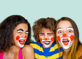 Two teen sisters and a little brother in the role of clowns posing in the studio