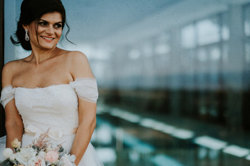 Bride in white dress in front of a window