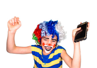 Portrait of happy funny clown kid holding smartphone and enjoying good news. Positive and expression concept.Isolated on white.pantomimic expression. emotions. April Fool's Day, April 1.