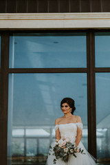 Bride with bouquet in front of a window