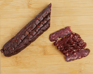 Pieces of sausage made from horse meat on a chopping Board.