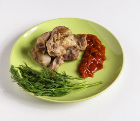 Pieces of roasted meat, tomato sauce and dill on a plate on a white background.