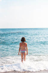 The girl goes into the sea water.