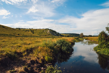 the hilly landscape of the Belgorod region . Sunny spring day with river and deep blue skies reflecting in the surface of the water and illuminated by the bright sun