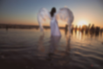 Fototapeta premium Blurry picture for background, Angel at sunset by the sea, good idea fantasy.
