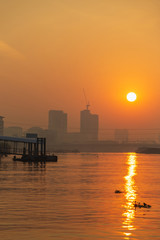 Obraz premium Pier by Chao phraya river with building and bridge at the morning.