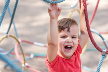 a child plays in a rope web on the playground in the park