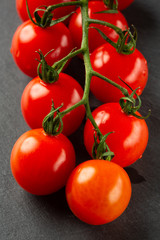 Part of cherry tomato branch on dark grey surface