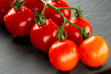 Delicious wet cherry tomatoes placed on the grey surface