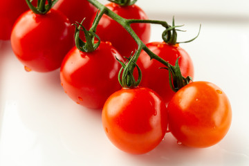 Close up of tomatoes with drops of water on white surface