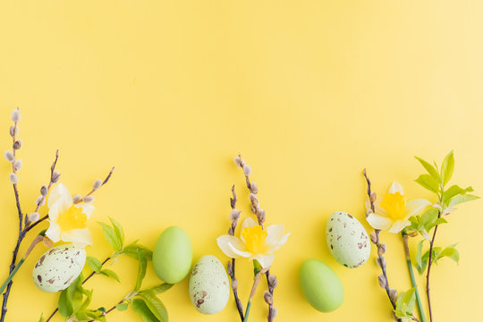 Flat lay easter composition with yellow daffodils and eggs on a yellow background