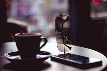 Morning coffee with a phone and glasses in the background