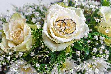 wedding rings on a bouquet of white roses