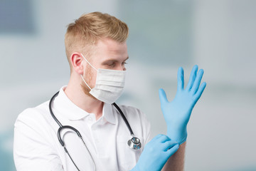 doctor with medical face mask puts on his medical gloves 