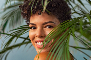 Beauty young woman smiling through palm leaves