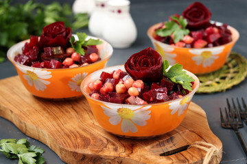Lean chickpea and beetroot salad on a wooden board against a dark background, decorated with beetroot roses