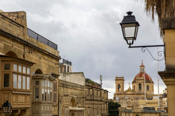 Traditional, wooden balcony and stone facade, typical for architecture of Gozo, Malta