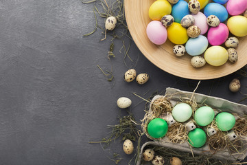 Colored Easter and quail eggs set on black table