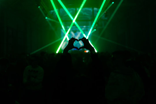 Woman showing heart symbol in the crowd on a party